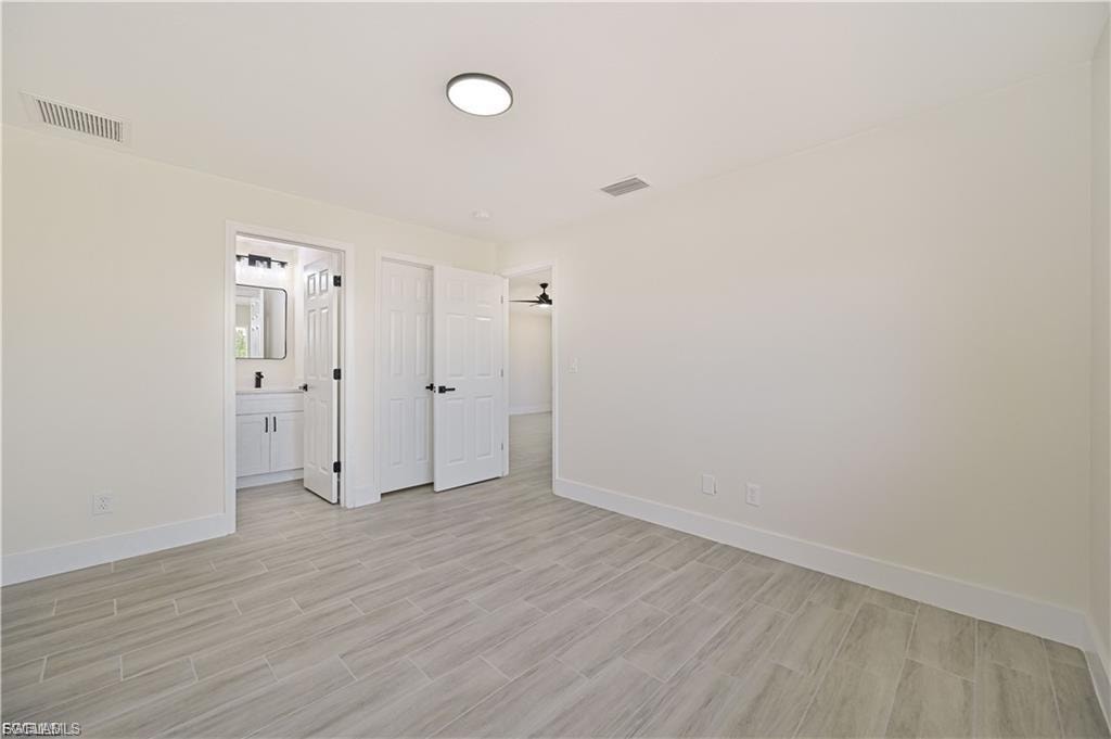 Spacious bedroom featuring wood-finish flooring, recessed ceiling lighting, and multiple closet doors providing ample storage