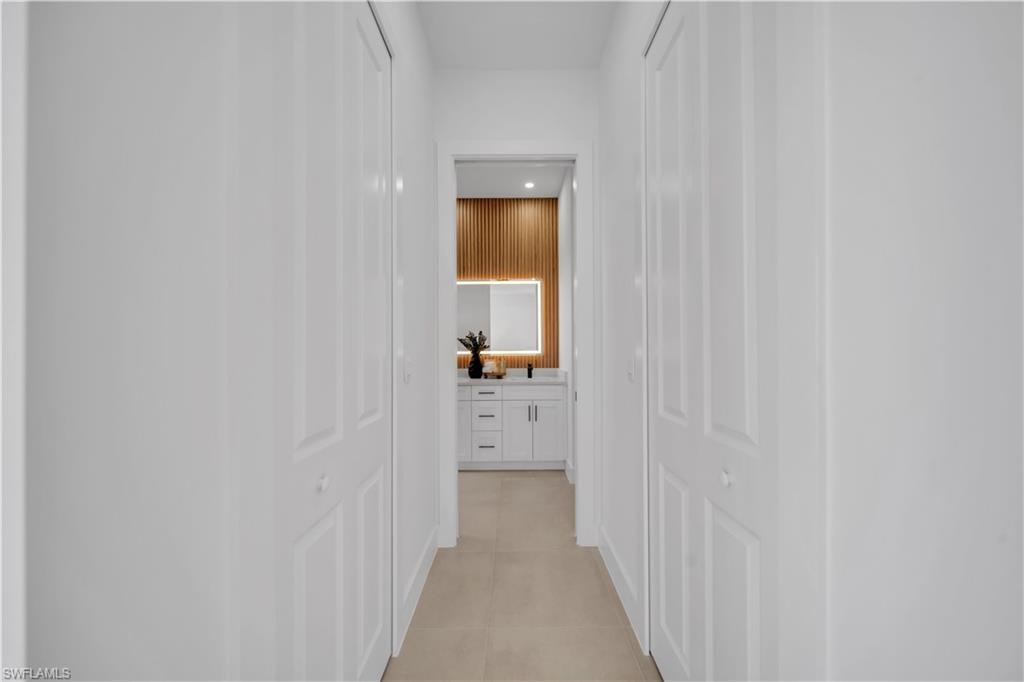 Hallway with neutral tile flooring and white bifold doors