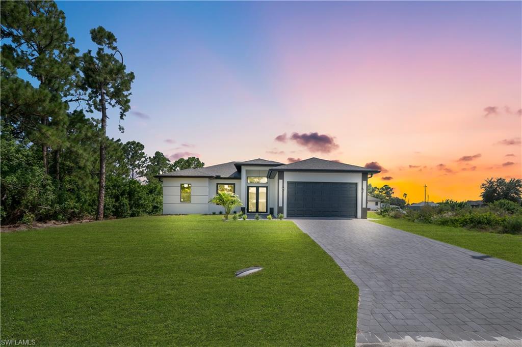 Modern facade with a dark gray garage door, a paved driveway, and an expansive lawn