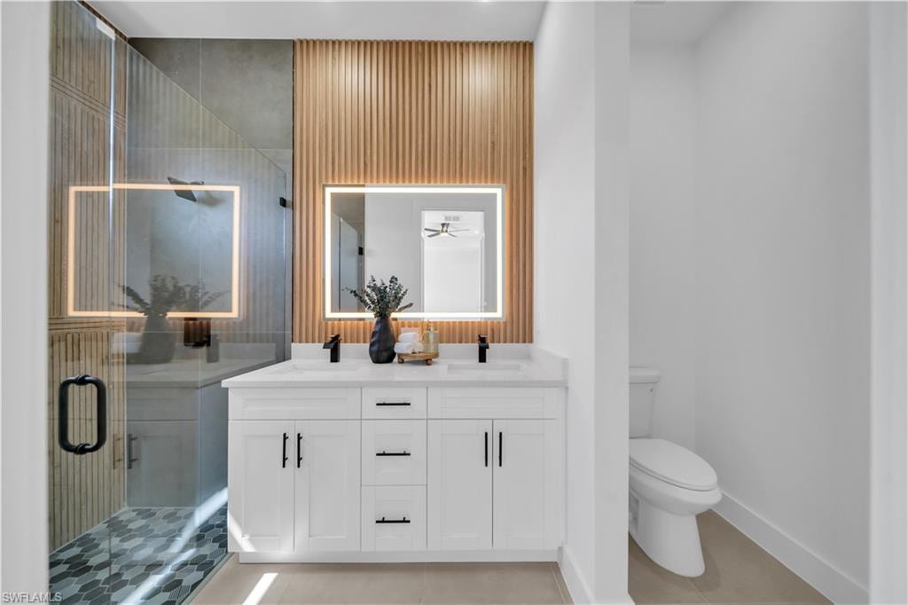 Dual vanity with white cabinetry, black hardware, and an illuminated mirror