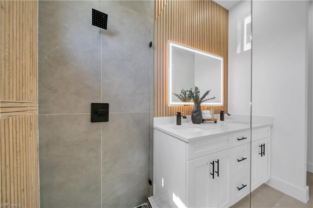 Glass-enclosed shower with matte black fixtures, full-height tile, and wood-panel accents
