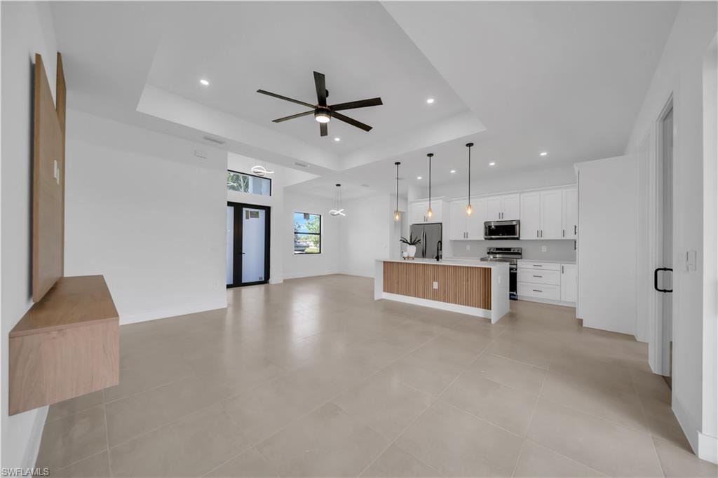 Expansive open-concept living space featuring a tray ceiling, recessed lighting, and a modern ceiling fan