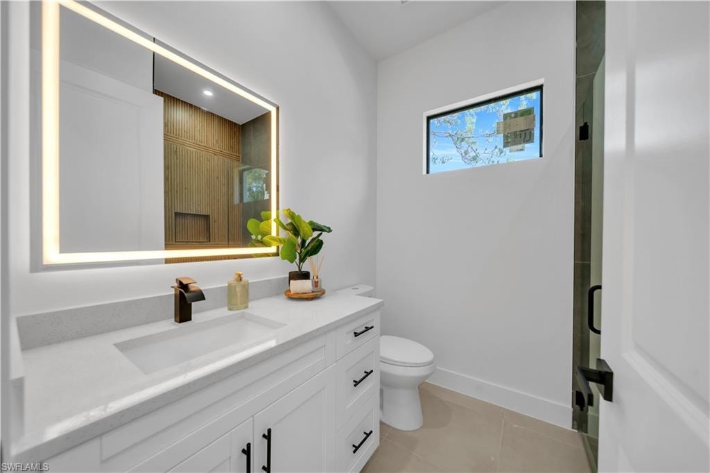 Vanity with integrated rectangular sink, bronze-tone faucet, and light-framed mirror