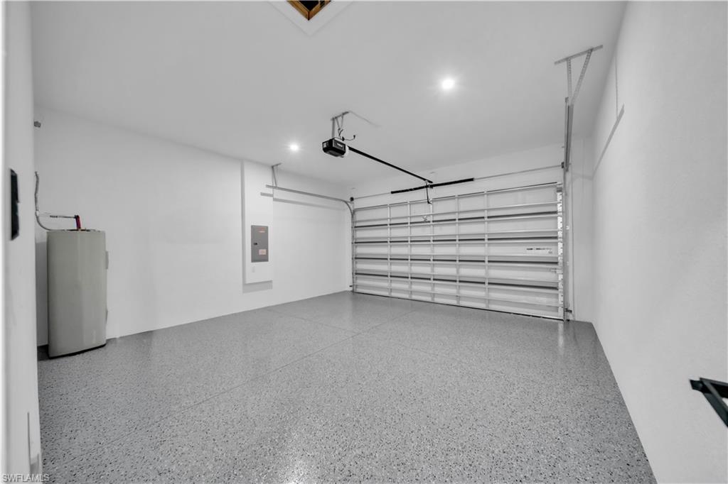Spacious garage featuring a roll-up door, automatic opener, recessed lighting, and a textured epoxy floor finish