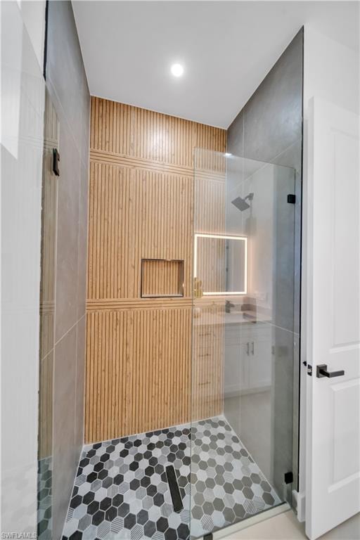 Glass-enclosed shower with textured wood-finish wall paneling, hexagonal tile flooring, and a recessed shower niche