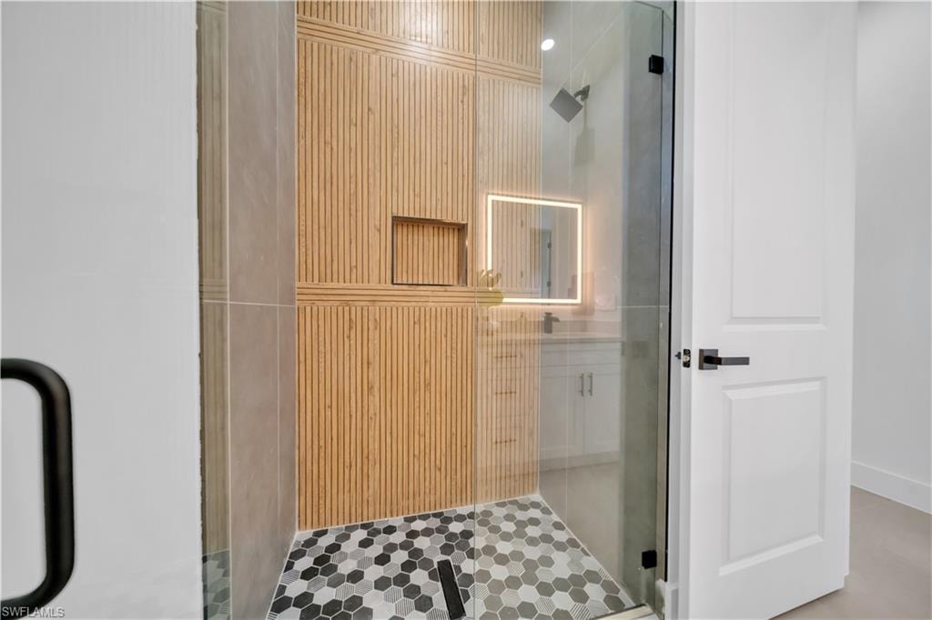 Glass-enclosed shower with wood-finish wall tile, a built-in shower niche, and hexagonal floor tiles