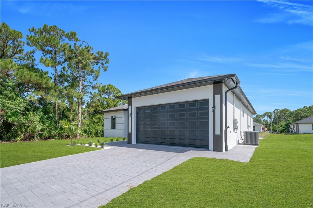 White exterior with dark trim accents, paver driveway, and a dark paneled garage door