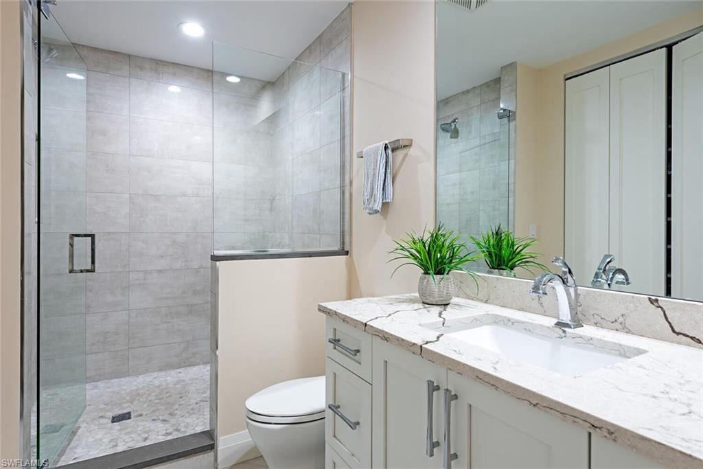 Bathroom with vanity, toilet, a stall shower, and recessed lighting