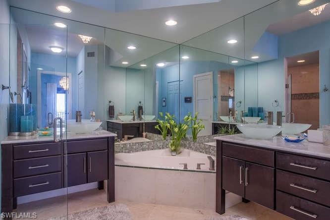 Bathroom featuring two vanities, a garden tub, recessed lighting, and tile patterned floors