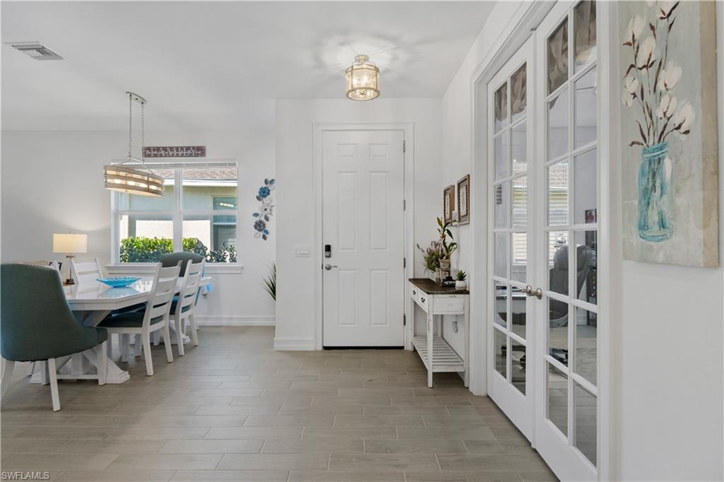 Bright foyer and hallway featuring neutral wood-finish flooring, recessed ceiling lighting, and white six-panel entry door
