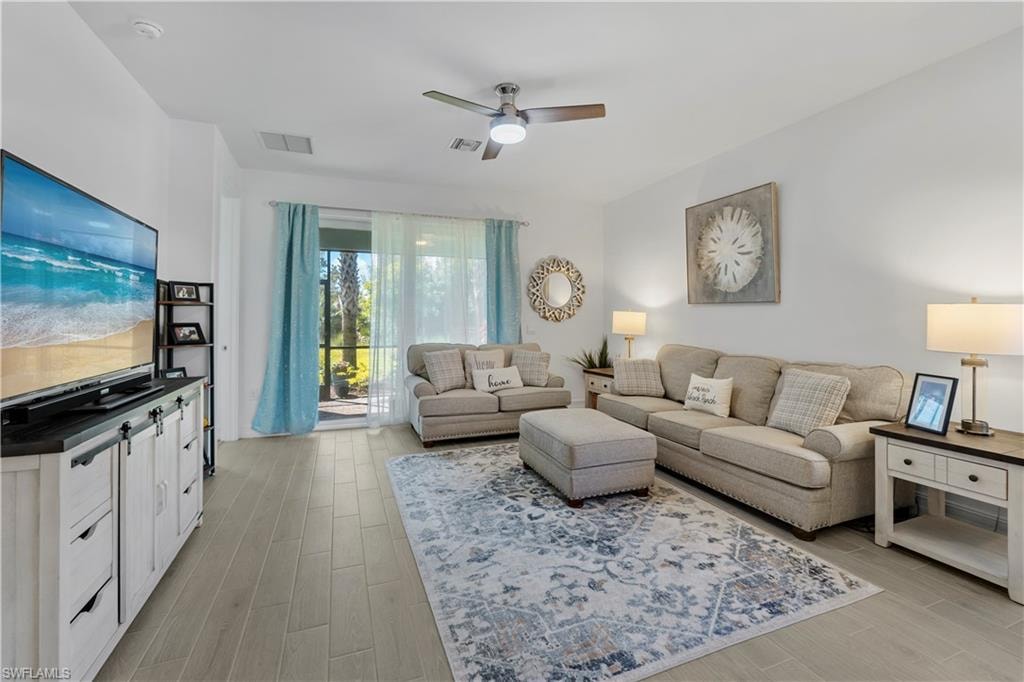 Recessed lighting, ceiling fan with light fixture, light wood-finish flooring, and sliding glass doors to a screened outdoor area