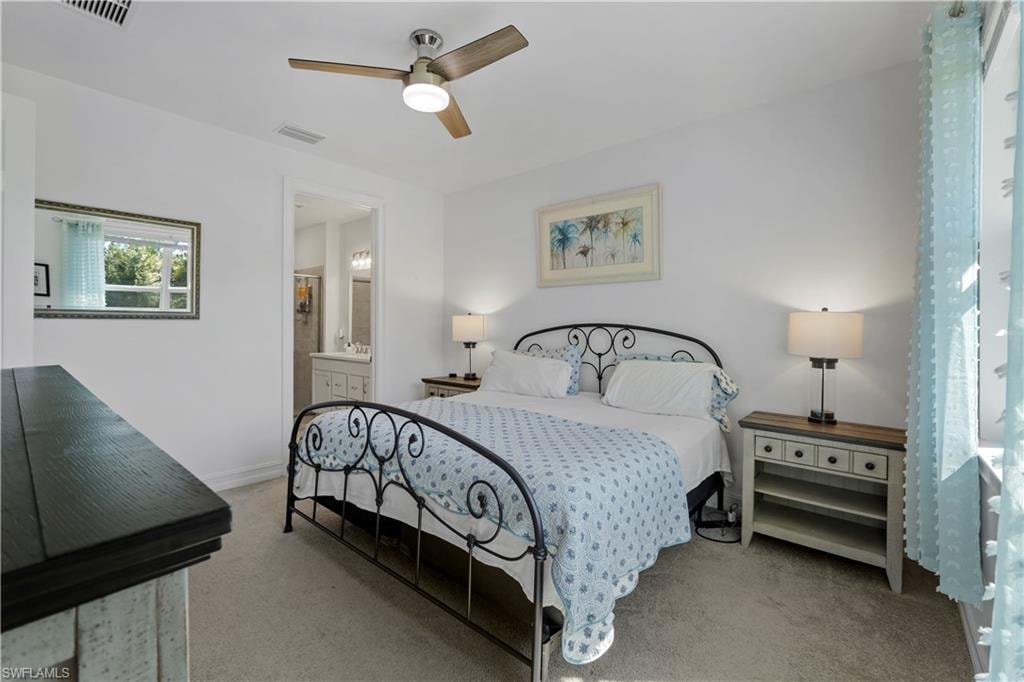 Ceiling fan with integrated lighting, carpeted flooring, window with vertical blinds, built-in shelving, and an open doorway to an adjoining bathroom