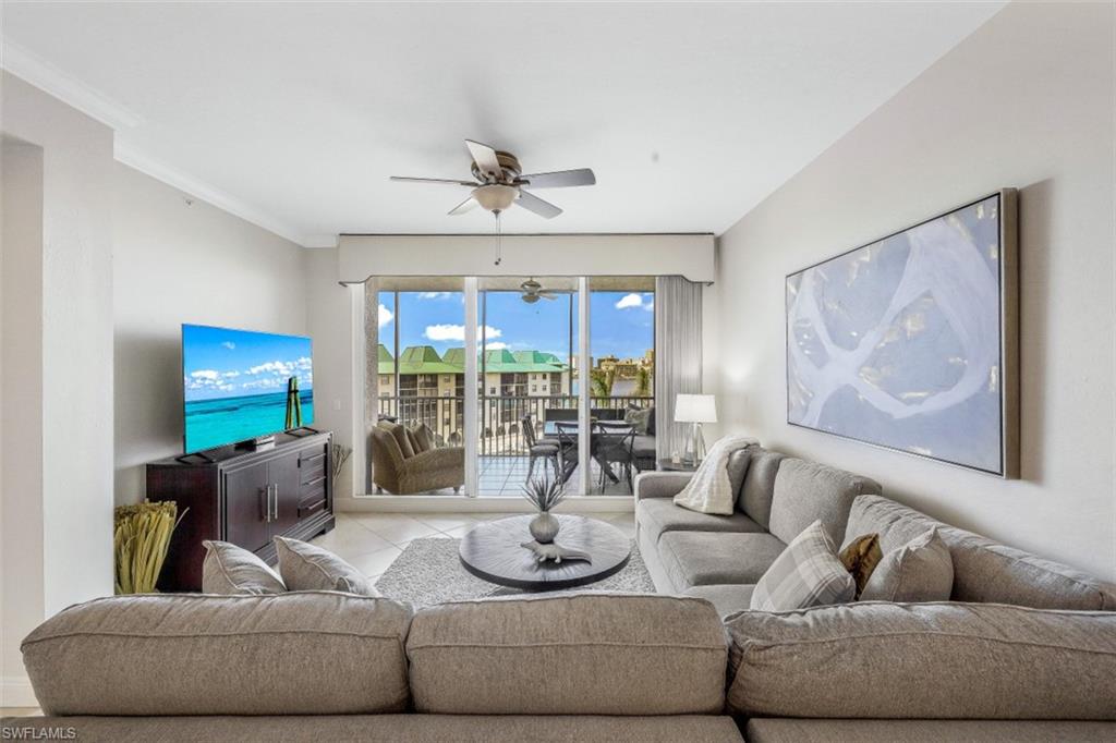 Living area with tile patterned floors, crown molding, and a ceiling fan