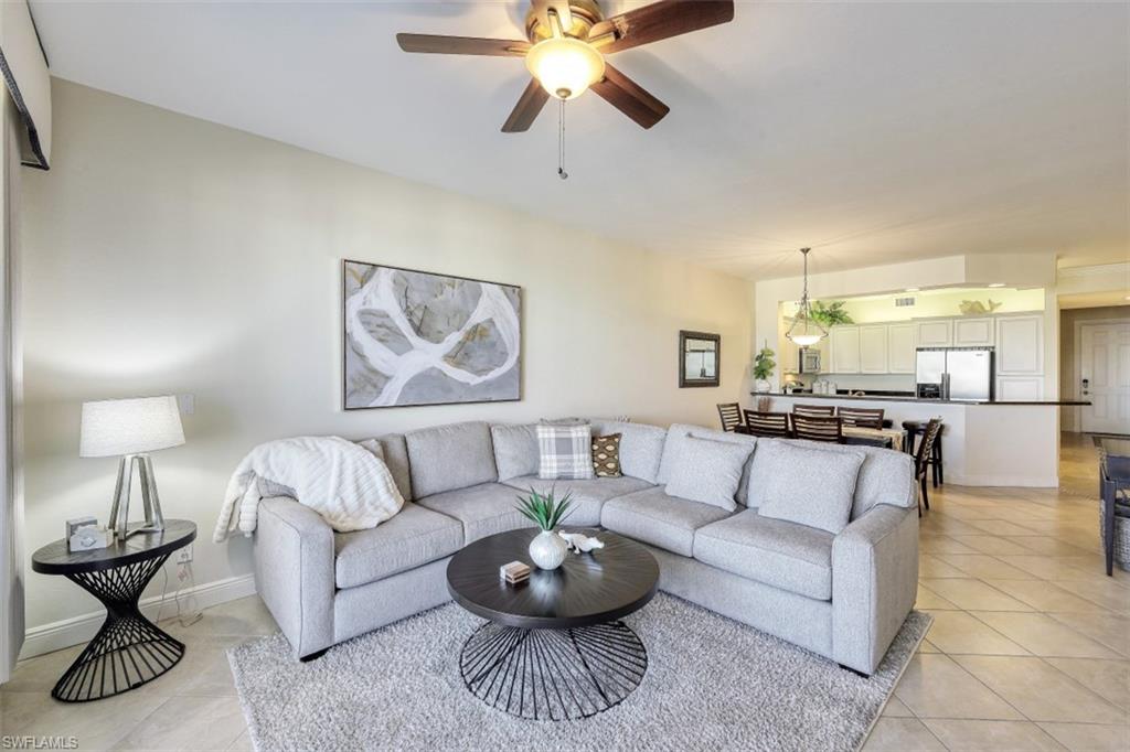 Living area with light tile patterned floors, a ceiling fan, and baseboards