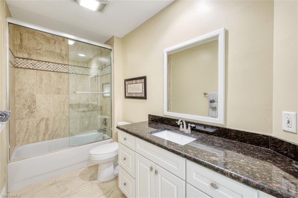 Full bath with combined bath / shower with glass door, visible vents, toilet, and vanity