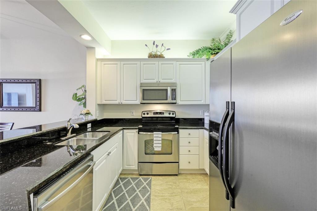 Kitchen with recessed lighting, dark stone countertops, appliances with stainless steel finishes, white cabinets, and a sink