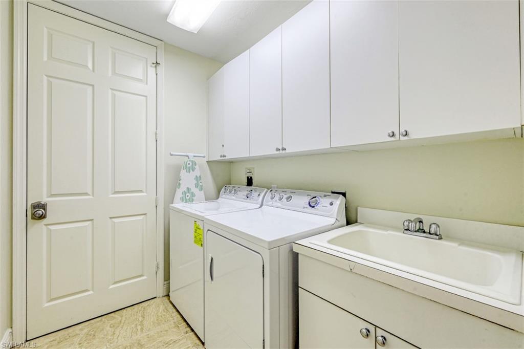 Washroom featuring cabinet space, washer and dryer, and a sink