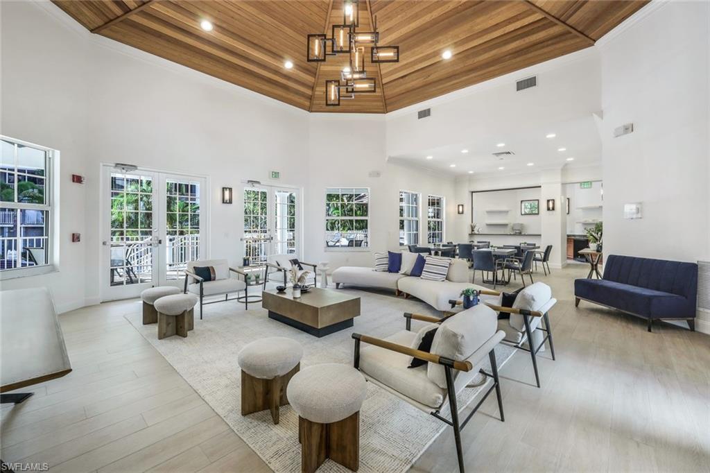 Living room with wooden ceiling, a towering ceiling, light wood-style floors, recessed lighting, and french doors