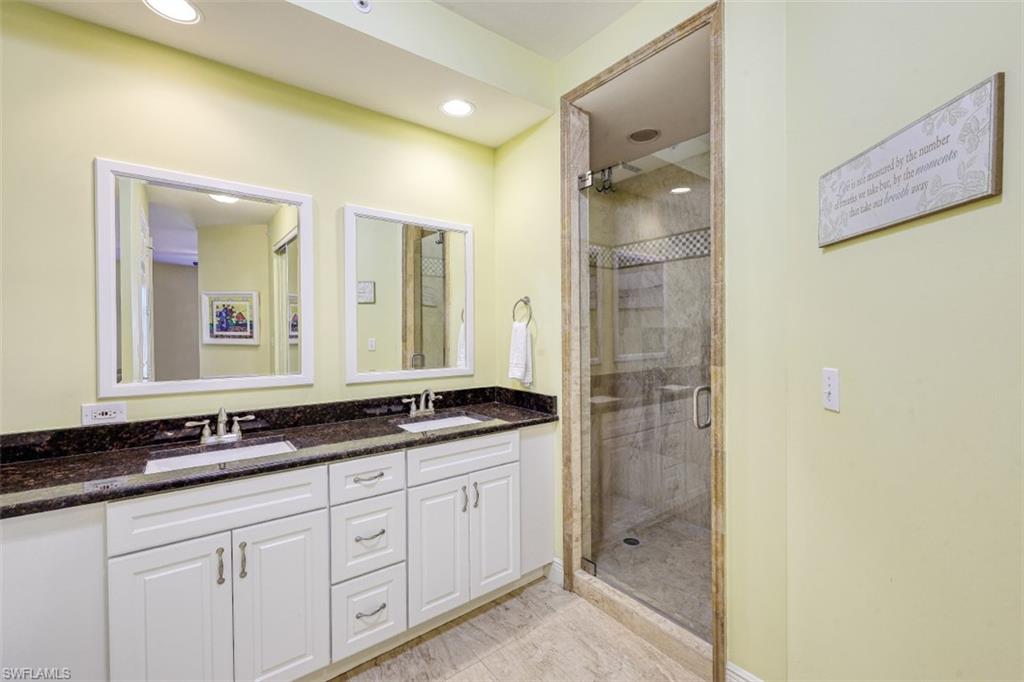 Bathroom with double vanity, a shower stall, and a sink