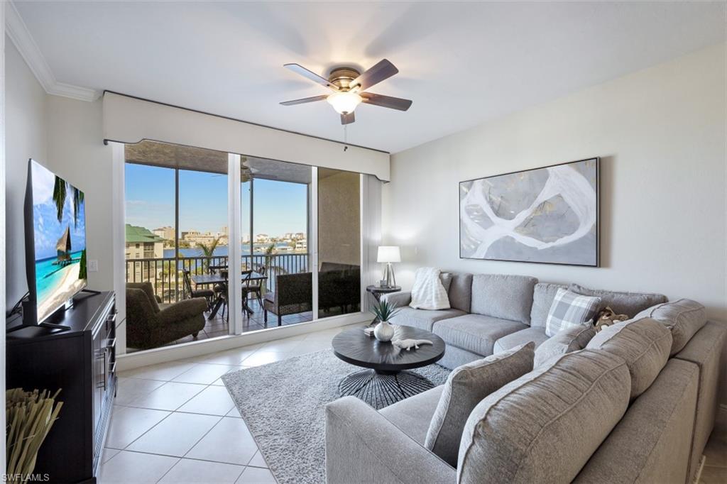 Living area featuring light tile patterned floors, ceiling fan, and crown molding