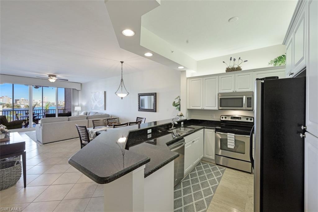 Kitchen with open floor plan, a peninsula, stainless steel appliances, and a sink