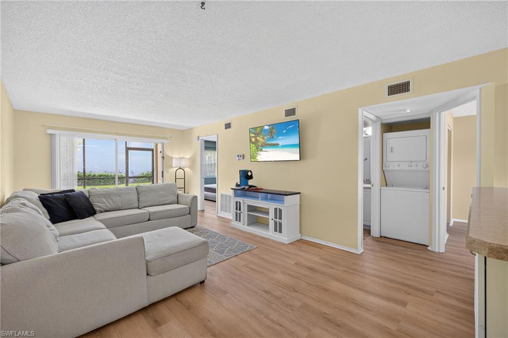 Wood-finish flooring throughout, bright walls, and a dedicated laundry area with stacked appliances