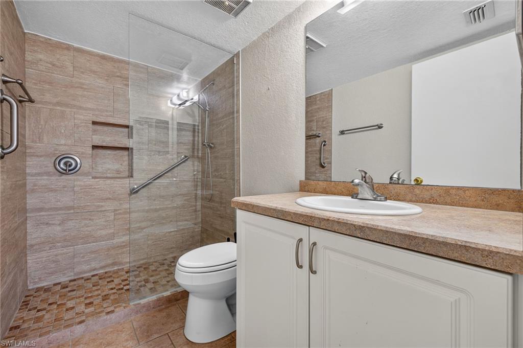 Walk-in shower with full-height tile surround, glass enclosure, and built-in shelving