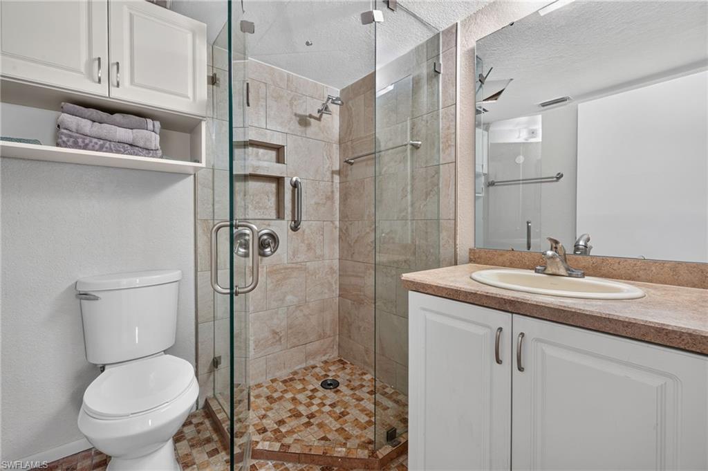 Glass-enclosed shower with a tiled surround, integrated shelving, and a mosaic tile floor