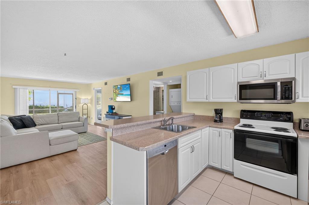 Open-concept kitchen with white cabinetry and stainless steel microwave