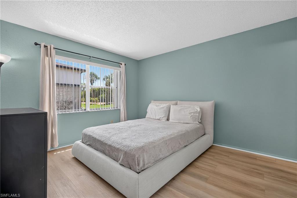 Hardwood-style flooring, a large window with vertical blinds, and a neutral wall color
