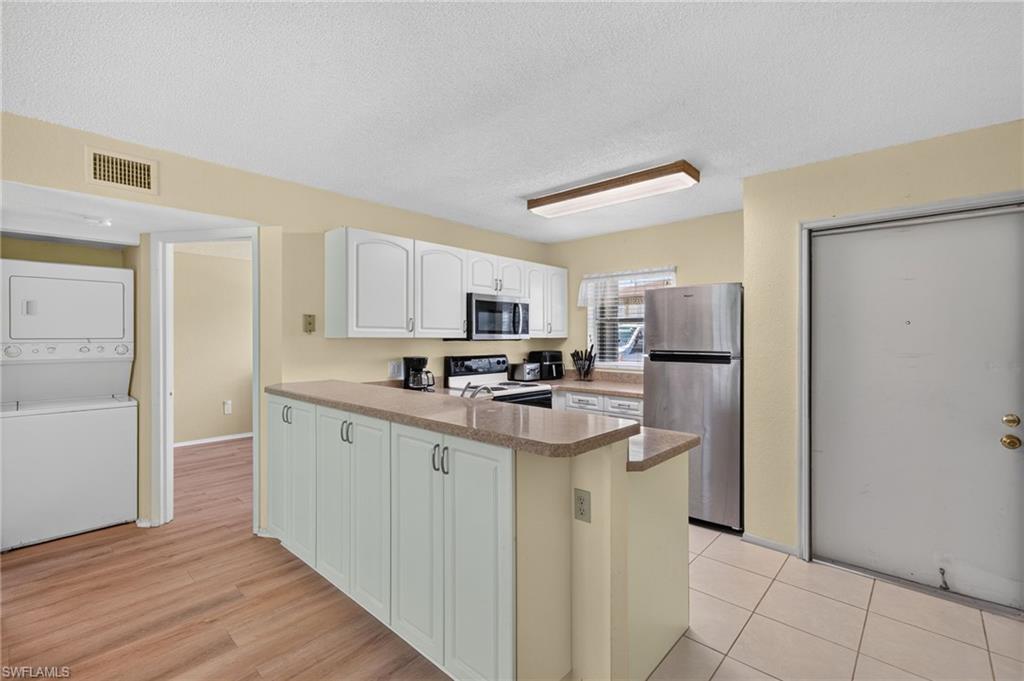 Kitchen featuring white cabinetry, stainless steel appliances, and a breakfast bar with a neutral-toned countertop