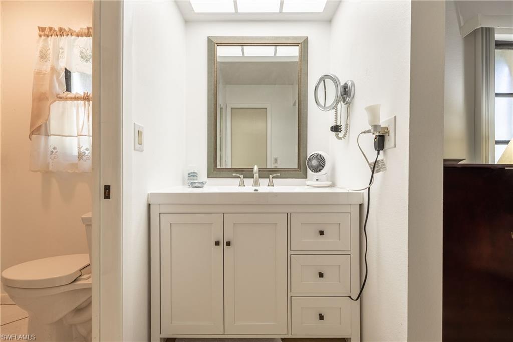 White vanity with shaker-style cabinetry, a built-in rectangular sink, and a framed mirror