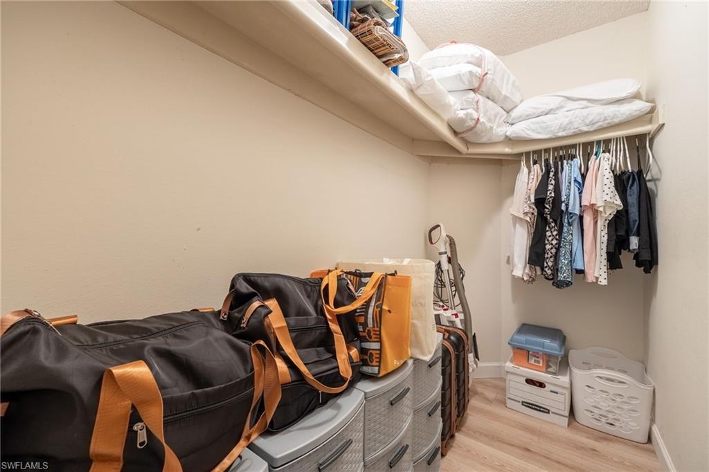Walk In closet with overhead shelving, clothes hanging rod, and wood-finish flooring