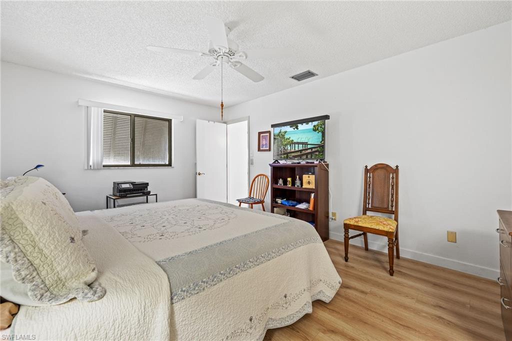 Wood-finish flooring, white ceiling fan, and window with horizontal blinds