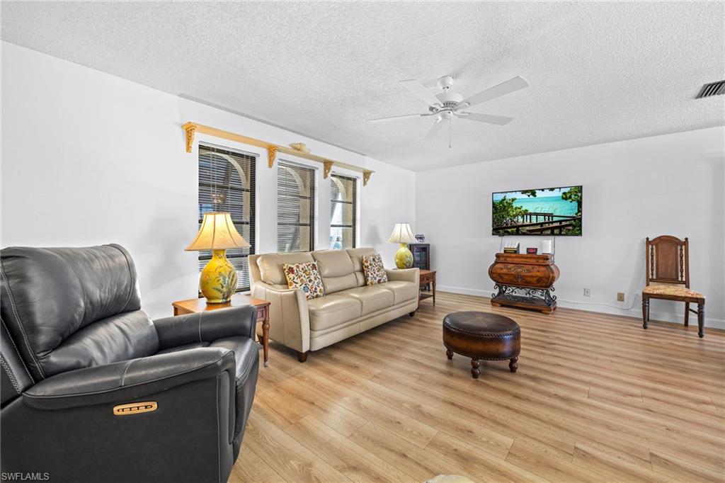 Wood-finish flooring, white walls, and a ceiling fan with integrated lighting