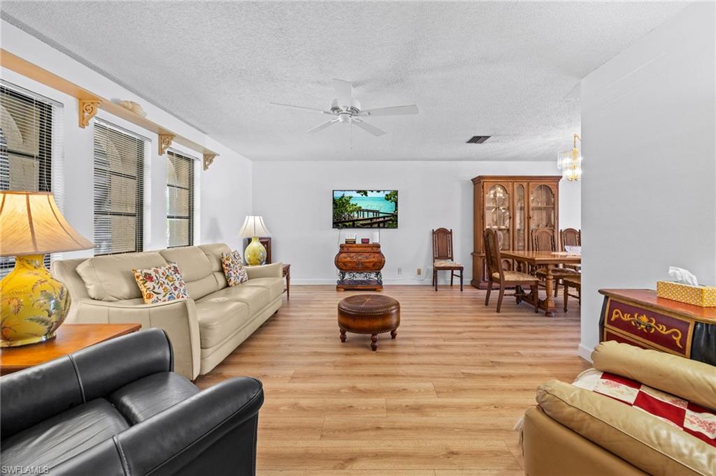 Wood-finish flooring, white walls, multiple windows with blinds, ceiling fan, and recessed lighting