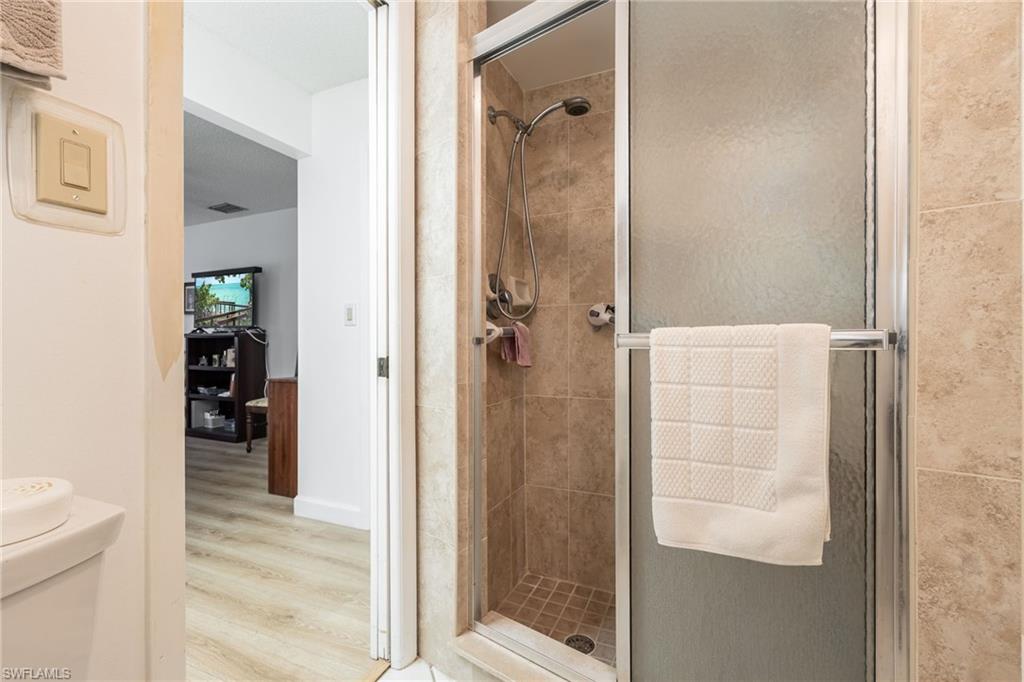 Shower with glass enclosure, handheld showerhead, and tiled walls