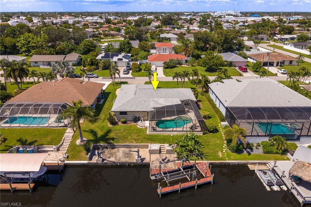 Waterfront property featuring a screened-in pool, private dock, and mature palm trees