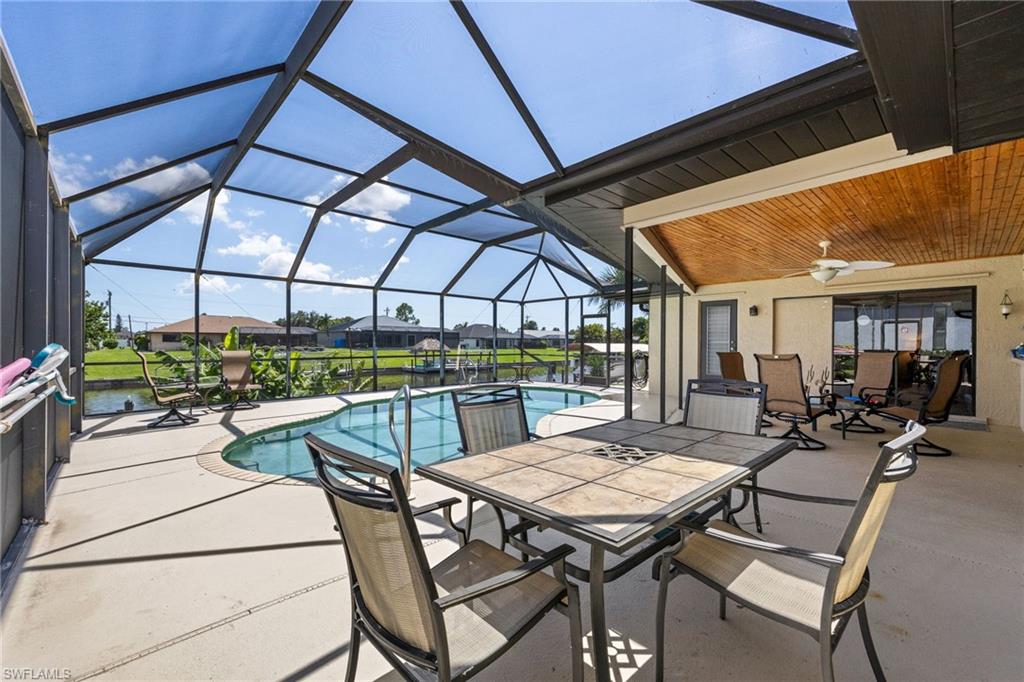 Screened lanai with a freeform pool, concrete decking, and a wood-paneled ceiling