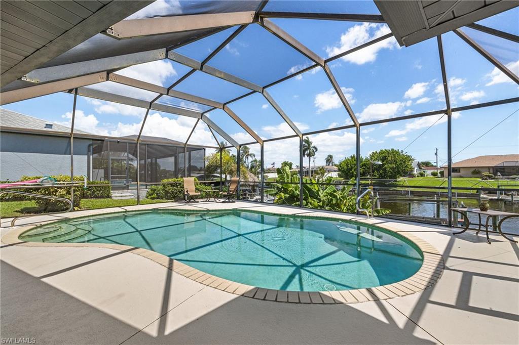 Screened outdoor pool area featuring a freeform pool, integrated steps, and light-colored coping