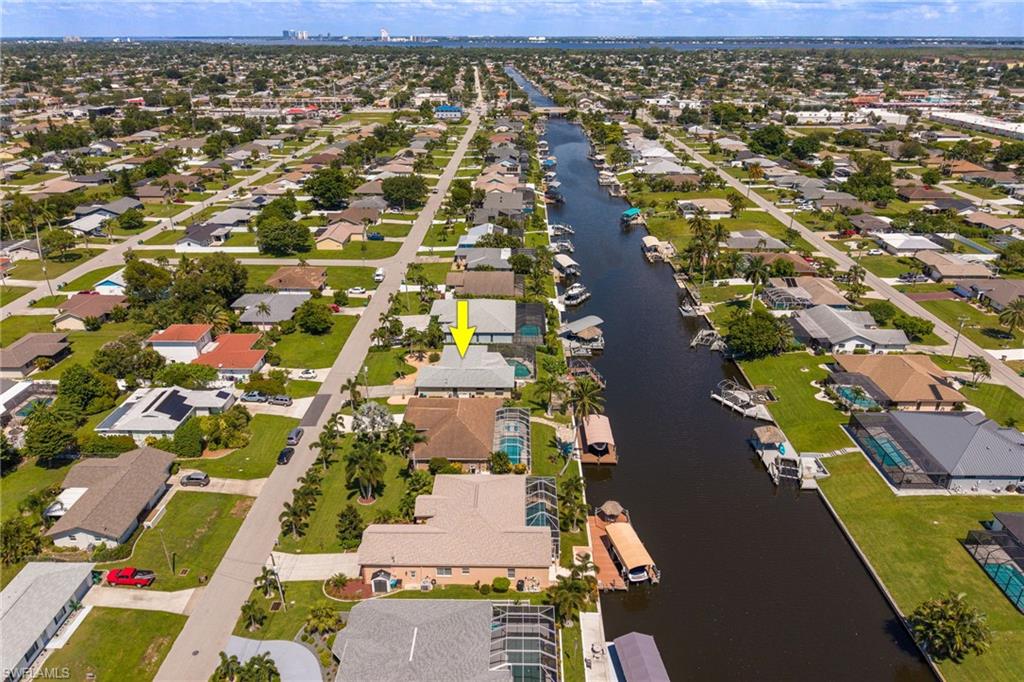 Waterfront property featuring a private boat dock, screened pool enclosure, mature landscaping, and a well-maintained lawn