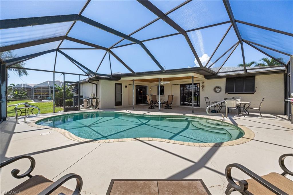 Screened pool enclosure with a freeform swimming pool, concrete patio, and covered patio area