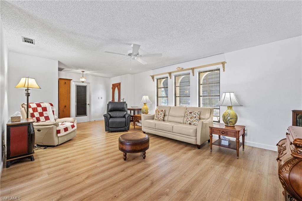 Bright living area featuring wood-finish flooring, white walls, and a ceiling fan