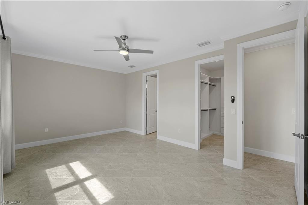 Spacious room featuring tile flooring, a modern ceiling fan, and access to a built-in closet system