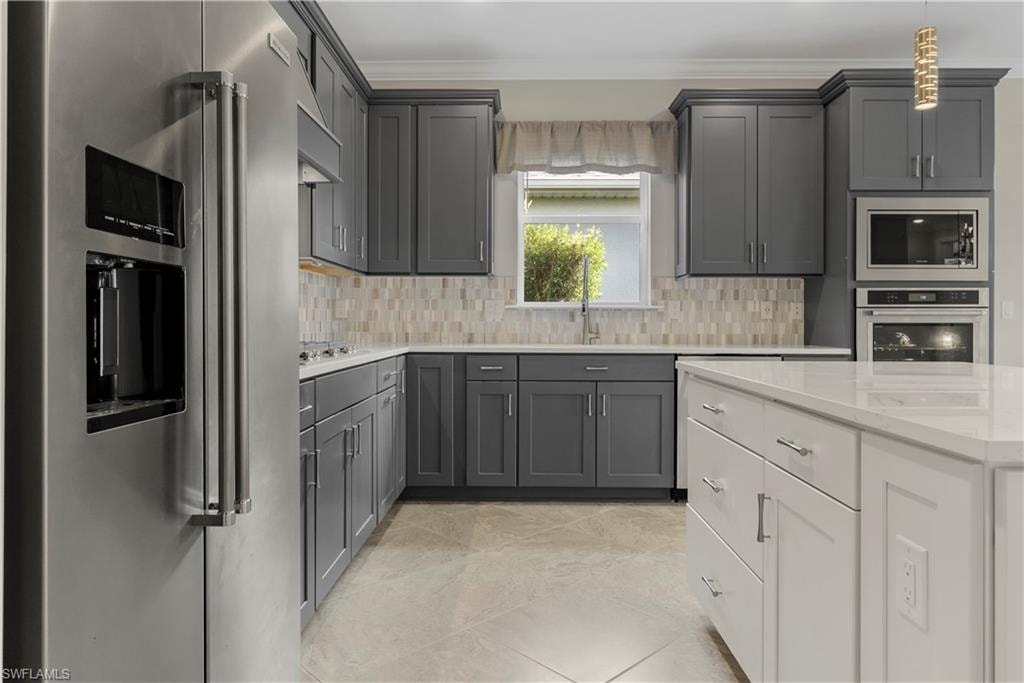 Kitchen featuring stainless steel refrigerator, built-in stainless steel microwave and oven, gray cabinetry, white countertops, and a white kitchen island
