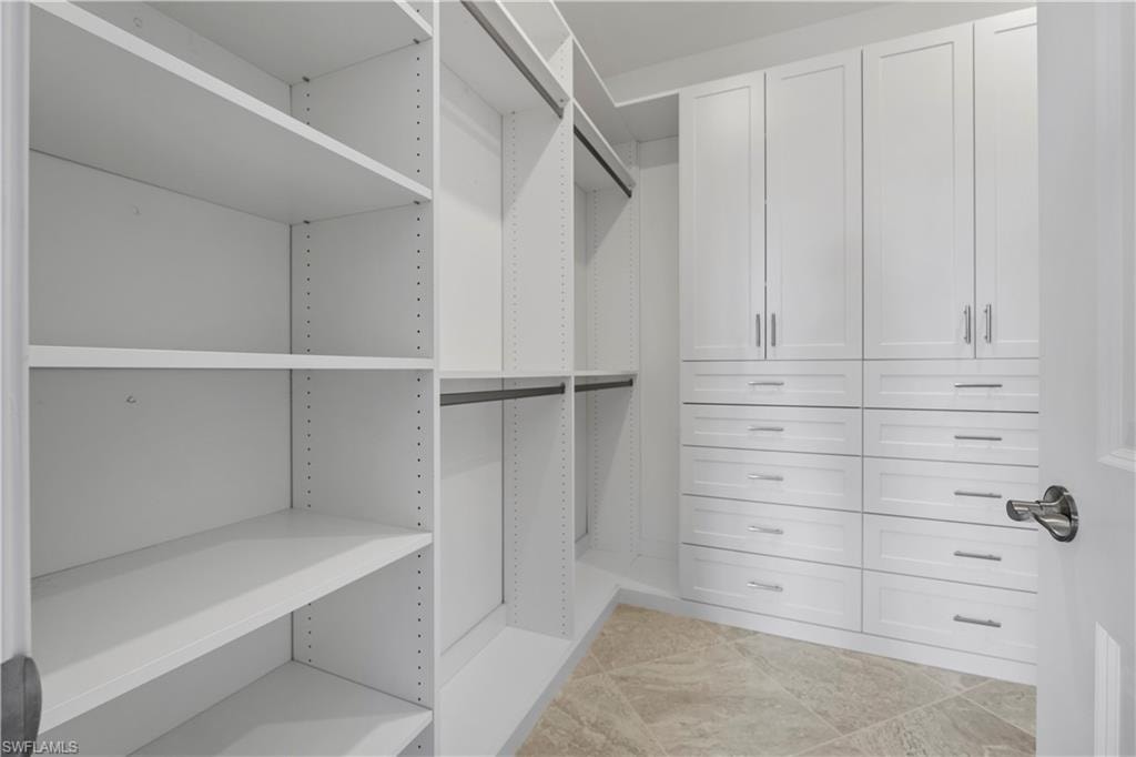 Built-in closet system featuring white shelving, multiple hanging rods, and integrated drawers with chrome pulls