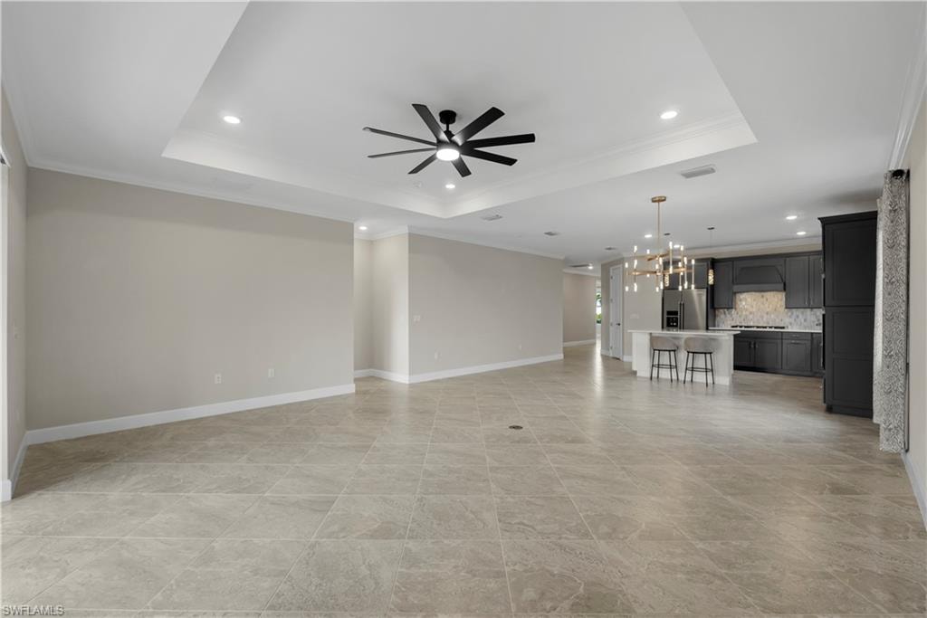 Expansive tiled flooring complemented by a tray ceiling with recessed lighting and a ceiling fan