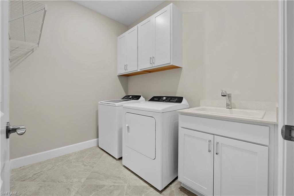 Laundry area featuring white cabinetry, a utility sink with a chrome faucet, and gray-toned tile flooring