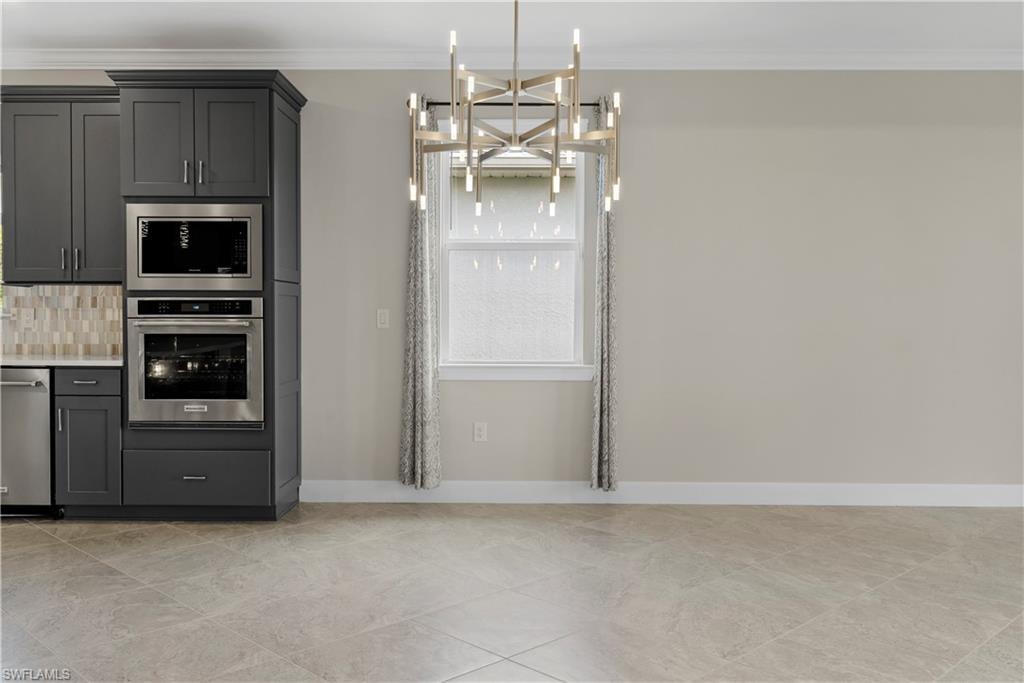 Gray shaker-style cabinetry with stainless steel appliances, tiled backsplash, and light-toned flooring
