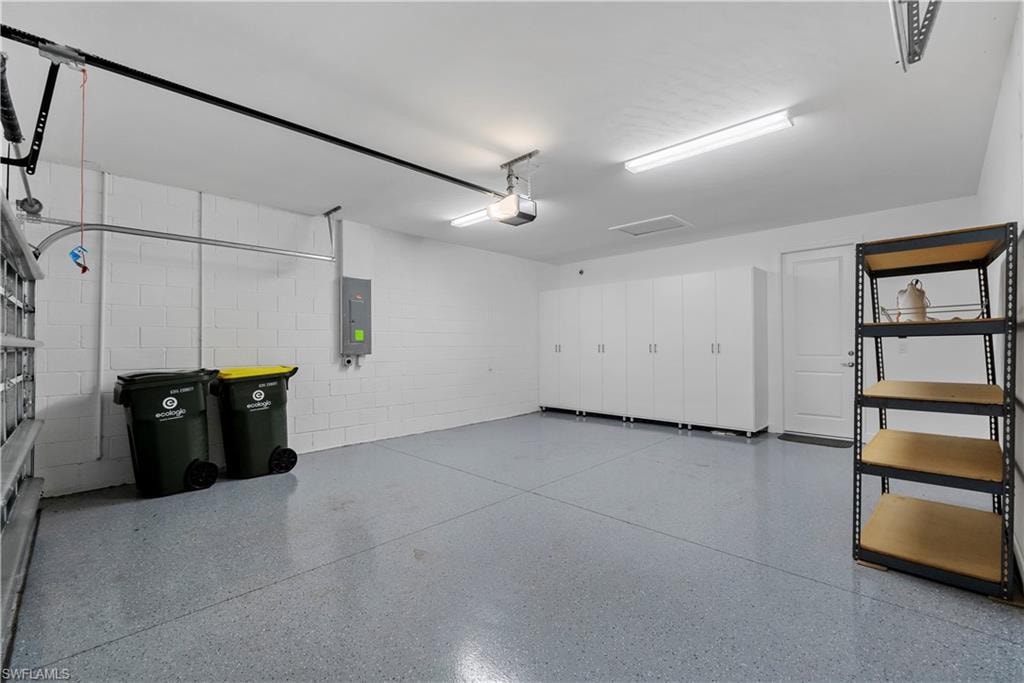 Epoxy-coated flooring, built-in storage cabinets, overhead lighting, and an overhead garage door mechanism